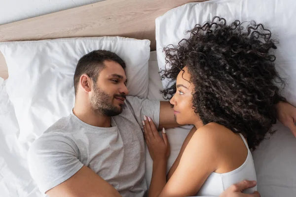 Top View Pleased Interracial Couple Looking Each Other While Lying — Stockfoto