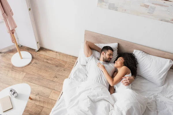 Vista Superior Positivo Interracial Casal Abraçando Deitado Cama — Fotografia de Stock