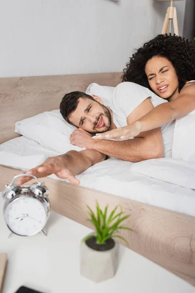 Displeased Interracial Couple Reaching Alarm Clock Morning — Stock Photo, Image