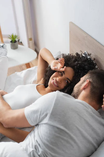 幸せなアフリカ系アメリカ人女性がベッドでボーイフレンドを見て — ストック写真