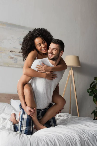 Neşeli Sakallı Adam Yatak Odasında Afrikalı Amerikalı Kız Arkadaşını Sırtında — Stok fotoğraf