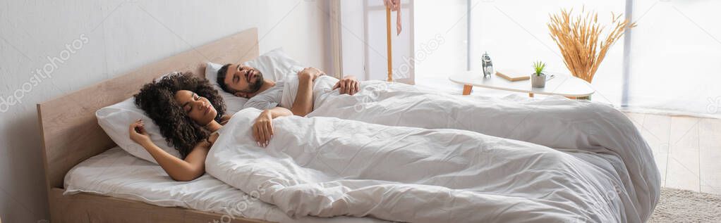 multiethnic couple sleeping together in bed, banner