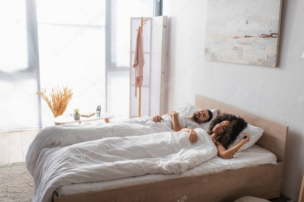 multiethnic couple sleeping together in bed