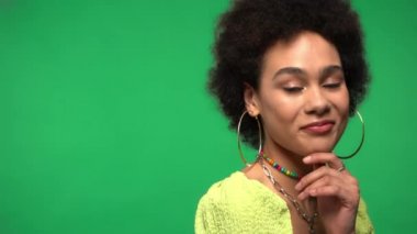 Yeşil küpe takan Afrikalı Amerikalı kadın izole edilmiş kameraya gülümsüyor. 
