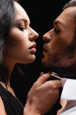 Genç bir adam ve seksi bir kadının yan görünüşü siyahta izole edilmiş.