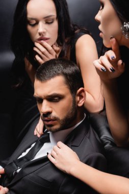 Tutkulu kadınlar siyah takım elbiseli genç işadamını baştan çıkarıyor.