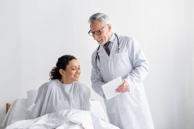 Gülümseyen doktor klinikteki Afrikalı Amerikalı kadınlara dijital tablet gösteriyor.