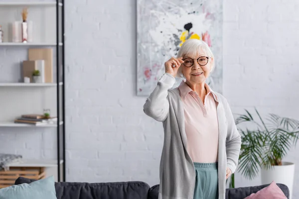 Leende Äldre Kvinna Som Håller Glasögon Vardagsrummet — Stockfoto