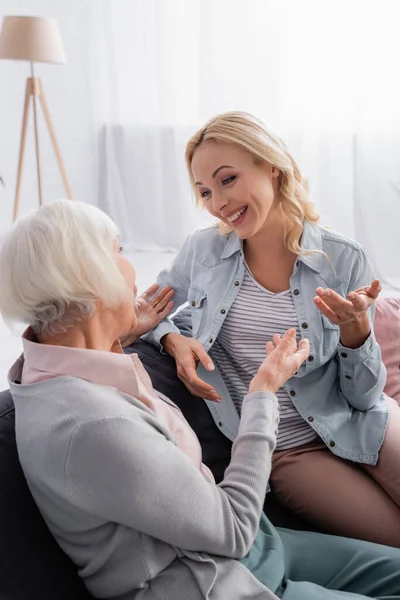 Leende Kvinna Tittar Äldre Mor Pekar Med Händerna Soffan — Stockfoto