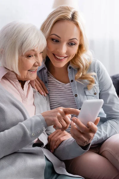 Χαμογελαστή Ηλικιωμένη Γυναίκα Που Χρησιμοποιεί Κινητό Τηλέφωνο Κοντά Στην Κόρη — Φωτογραφία Αρχείου
