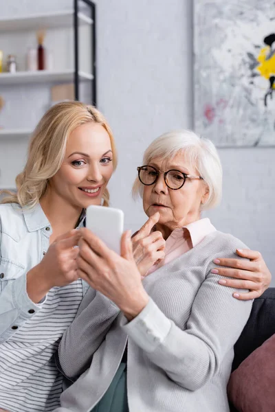 Mujer Mayor Sosteniendo Teléfono Móvil Cerca Hija Sonriente — Foto de Stock