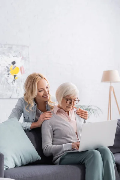 Smiling Woman Hugging Senior Parent Using Laptop — Stock Photo, Image