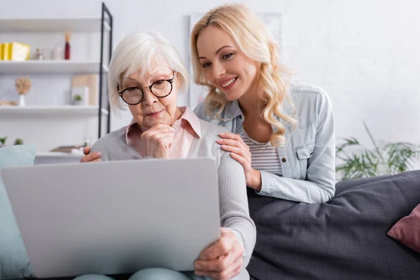 Старшая Женщина Использует Ноутбук Размытом Переднем Плане Рядом Дочерью — стоковое фото