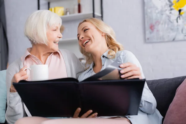 Cheerful Women Cup Holding Photo Album Blurred Foreground — Stock Photo, Image