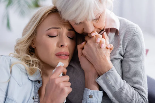 Elderly woman calming displeased and crying daughter