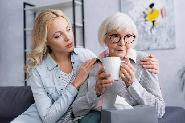 Vrouw Knuffelen Trieste Ouder Met Kopje Buurt Wazig Servet — Stockfoto