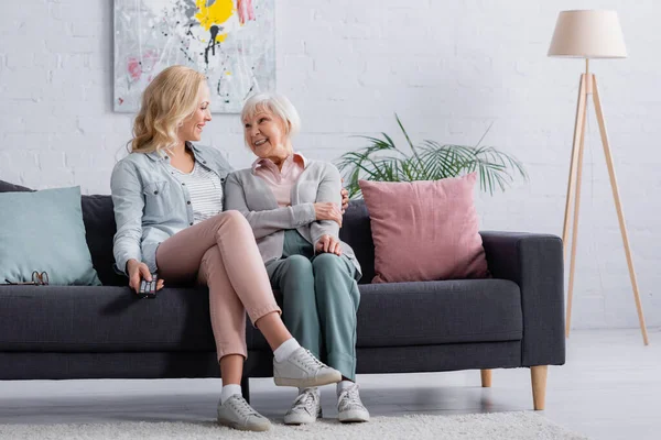 Uzaktan kumandalı yaşlı anneyi kucaklayan kadın. 