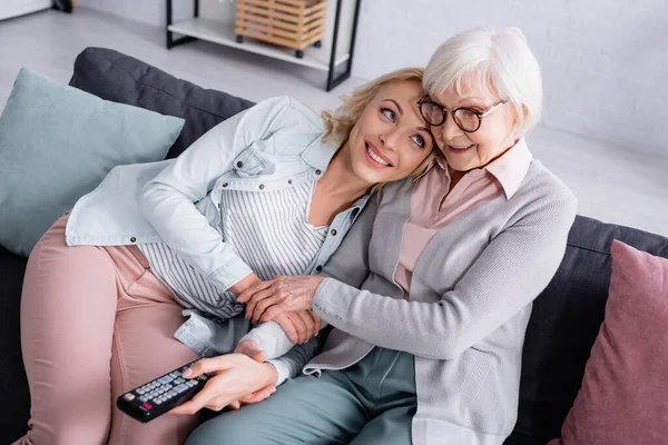 Lächelnde Seniorin Schaut Film Der Nähe Ihrer Tochter Mit Fernbedienung — Stockfoto