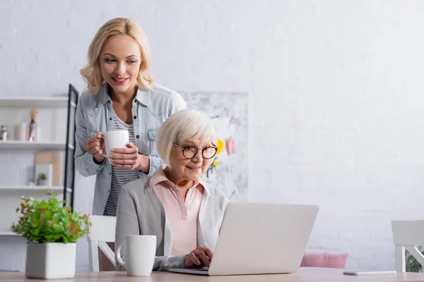 Smiling Woman Cup Sanding Mother Using Laptop — Stock Photo, Image