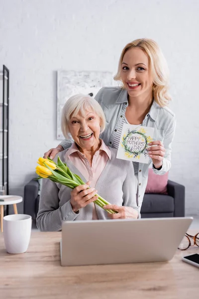 Smiling Senior Woman Holding Flowers Daughter Greeting Card Laptop — Stock Photo, Image
