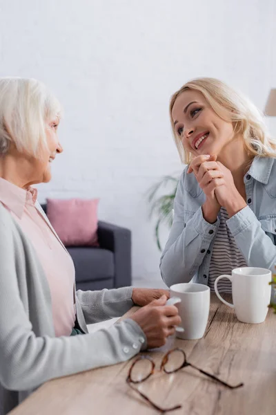 Mulher Positiva Conversando Com Mãe Com Xícara Chá Perto Óculos — Fotografia de Stock