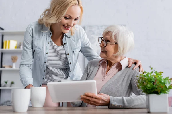 Mujer Sonriente Abrazando Madre Con Tableta Digital Cerca Las Copas — Foto de Stock