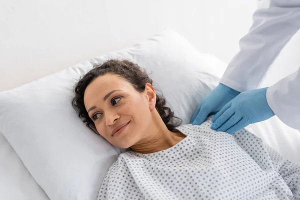 Doctor Guantes Látex Tocando Hombro Mujer Afroamericana Sonriente Acostada Cama —  Fotos de Stock