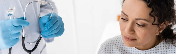 戴乳胶手套的医生手持听诊器靠近非洲裔美国妇女诊所 — 图库照片