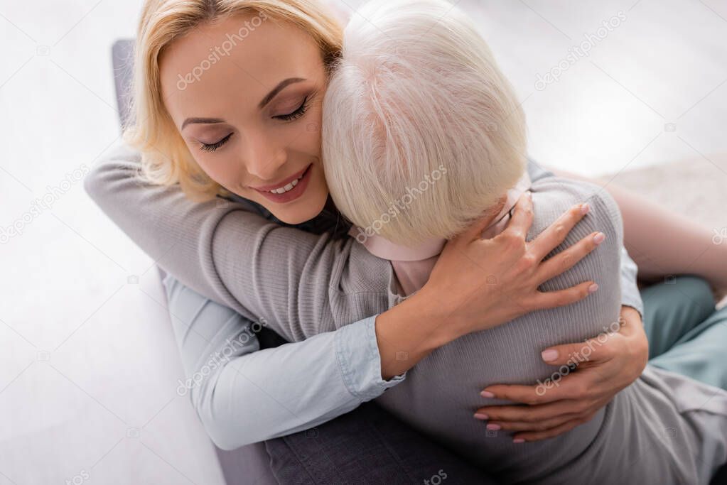 Overhead view of woman with closed eyes hugging grey haired mother 