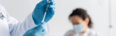 cropped view of doctor in latex gloves holding syringe with vaccine near african american woman on blurred background, banner clipart