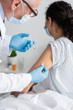 Tıbbi maskeli doktor Afrikalı Amerikalı kadınlara aşı enjekte ediyor.