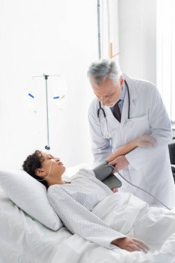 Doktor, klinikteki hasta Afrikalı Amerikalı kadının eline tonometre kelepçesi taktı.