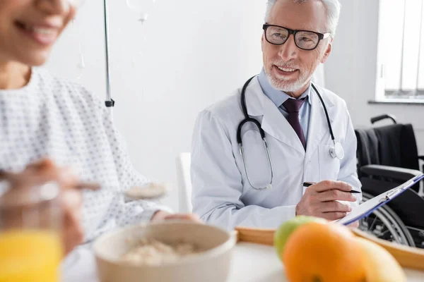 Médico Sonriente Escribiendo Prescripción Cerca Mujer Afroamericana Desayunando Primer Plano — Foto de Stock