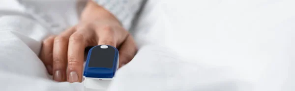 cropped view of woman with pulse oximeter on finger, banner