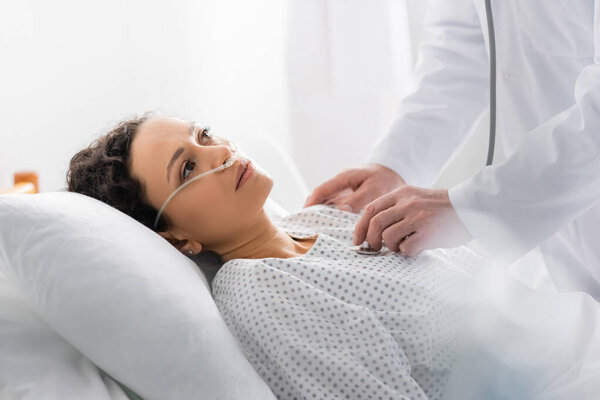 врач осматривает больную африканскую американку со стетоскопом на размытом переднем плане