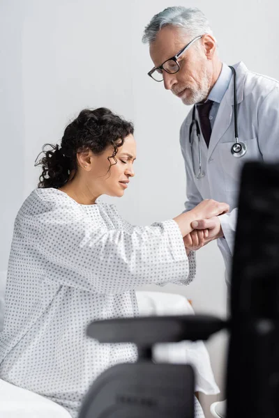 Attentive Doctor Supporting African American Woman Frowning Pain Wheelchair Blurred — Stock Photo, Image