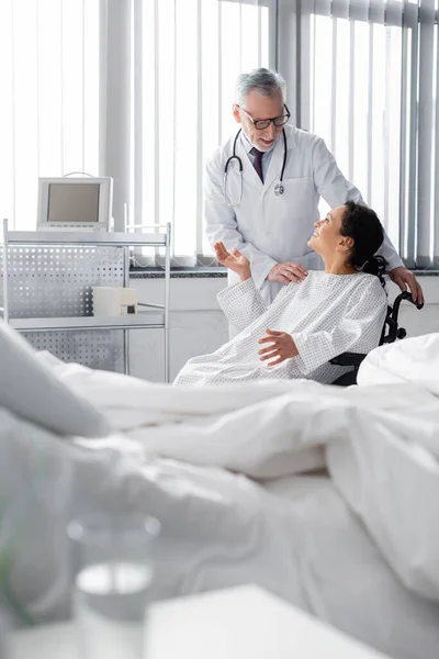 Happy African American Woman Wheelchair Gesturing While Talking Doctor Bed — Stock Photo, Image