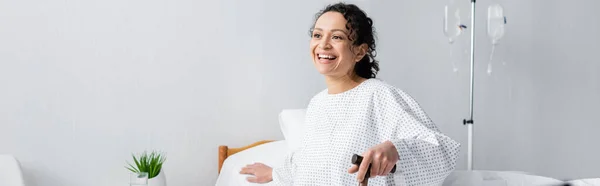 Alegre Mujer Afroamericana Sentada Con Bastón Cama Clínica Pancarta — Foto de Stock