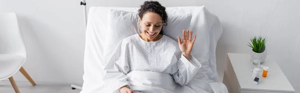 Alegre Africano Americano Mulher Acenando Mão Enquanto Sentado Cama Hospital — Fotografia de Stock