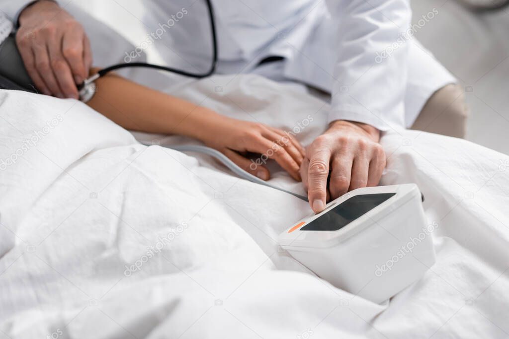 cropped view of doctor measuring blood pressure of woman with tonometer