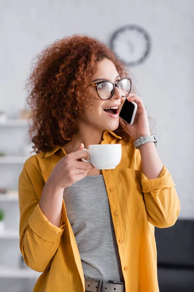 Mulher Espantada Óculos Falando Telefone Celular Enquanto Segurando Xícara Café — Fotografia de Stock