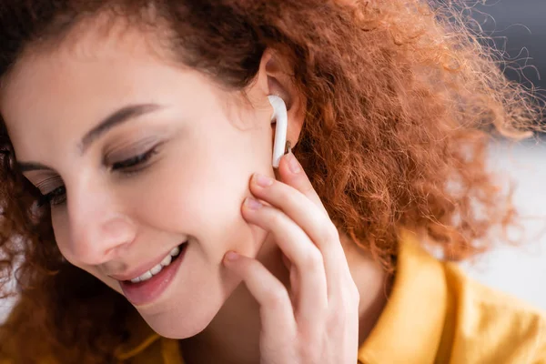 Gelukkig Vrouw Met Golvend Haar Aanpassen Oortelefoon Tijdens Het Luisteren — Stockfoto