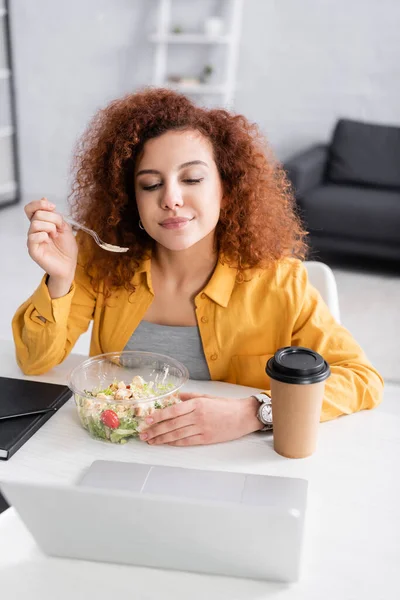 Freelancer Encaracolado Comendo Salada Fresca Perto Laptop Primeiro Plano Desfocado — Fotografia de Stock