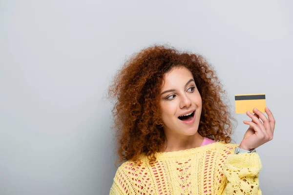 Astonished Woman Wavy Hair Looking Credit Card Grey Background — Stock Photo, Image