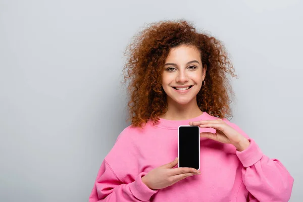 Χαρούμενη Γυναίκα Δείχνει Smartphone Λευκή Οθόνη Απομονωμένη Γκρι — Φωτογραφία Αρχείου