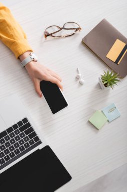 Bilgisayarın ve kredi kartının yanında elinde boş ekranla akıllı telefon tutan bir kadın görüntüsü.