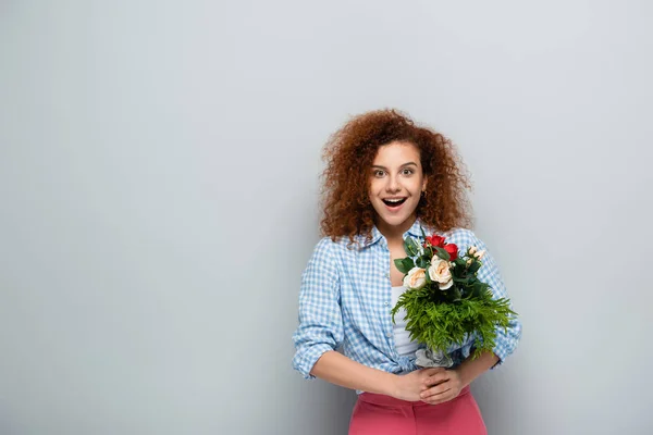 Förvånad Kvinna Tittar Kameran Medan Håller Blommor Grå Bakgrund — Stockfoto