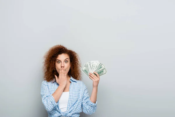 Zdumiona Kobieta Zakrywając Usta Dłonią Trzymając Pieniądze Szarym Tle — Zdjęcie stockowe