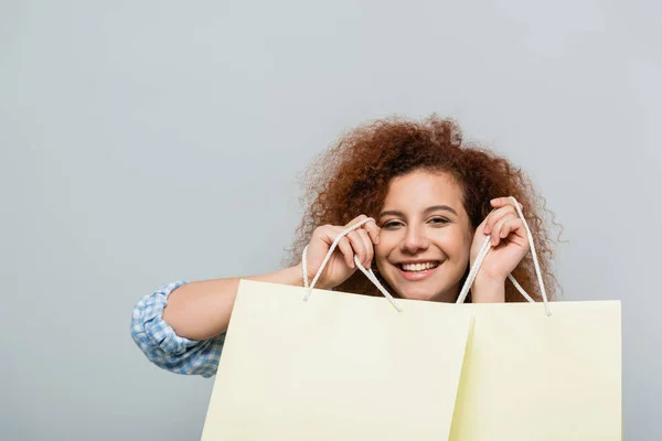 Neşeli Kıvırcık Bir Kadın Alışveriş Çantalarını Gri Renkte Tutuyor — Stok fotoğraf