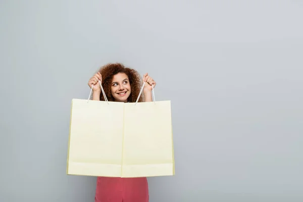 Mujer Feliz Rizada Mirando Hacia Otro Lado Mientras Sostiene Bolsas — Foto de Stock